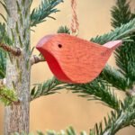 A wooden robin tree decoration hanging in a christmas tree.