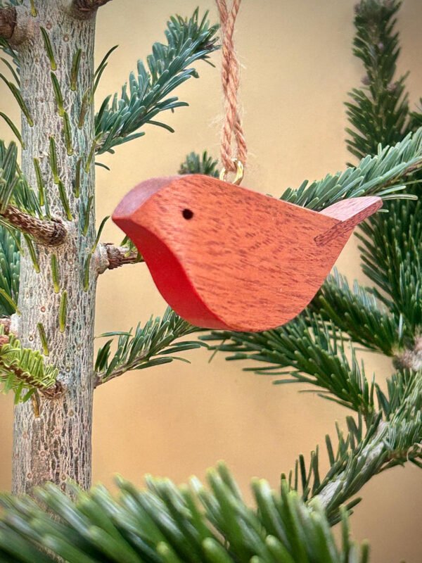 A wooden robin tree decoration hanging in a christmas tree.